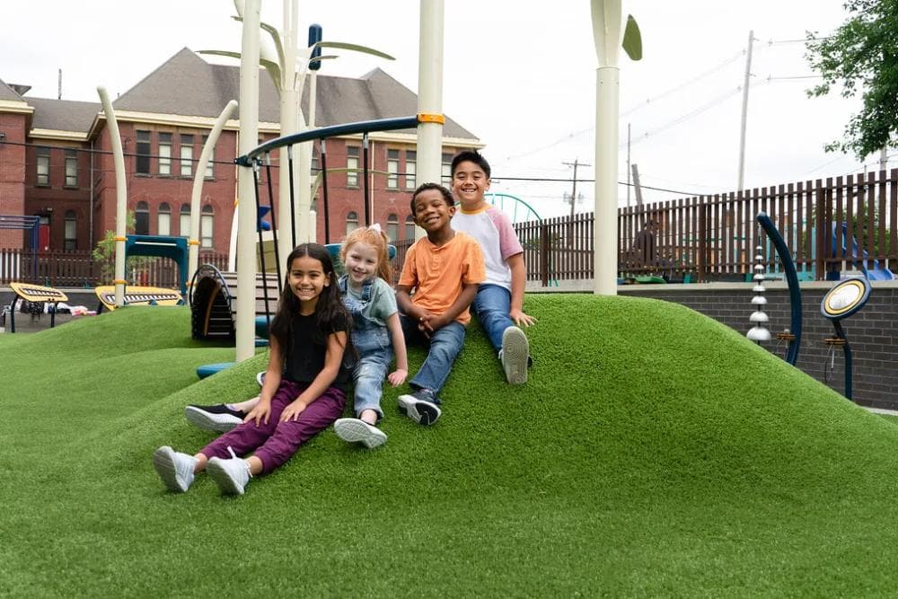 Modular playground structure with slides, tree-shaped panels and climbing steps on engineered wood fiber surfacing